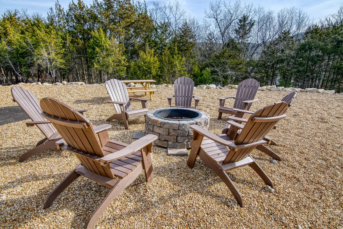 A cozy fire pit surrounded by Adirondack chairs and tall trees, perfect for evening gatherings and storytelling under the stars. The rustic setting encourages communal experiences and memorable moments in nature.