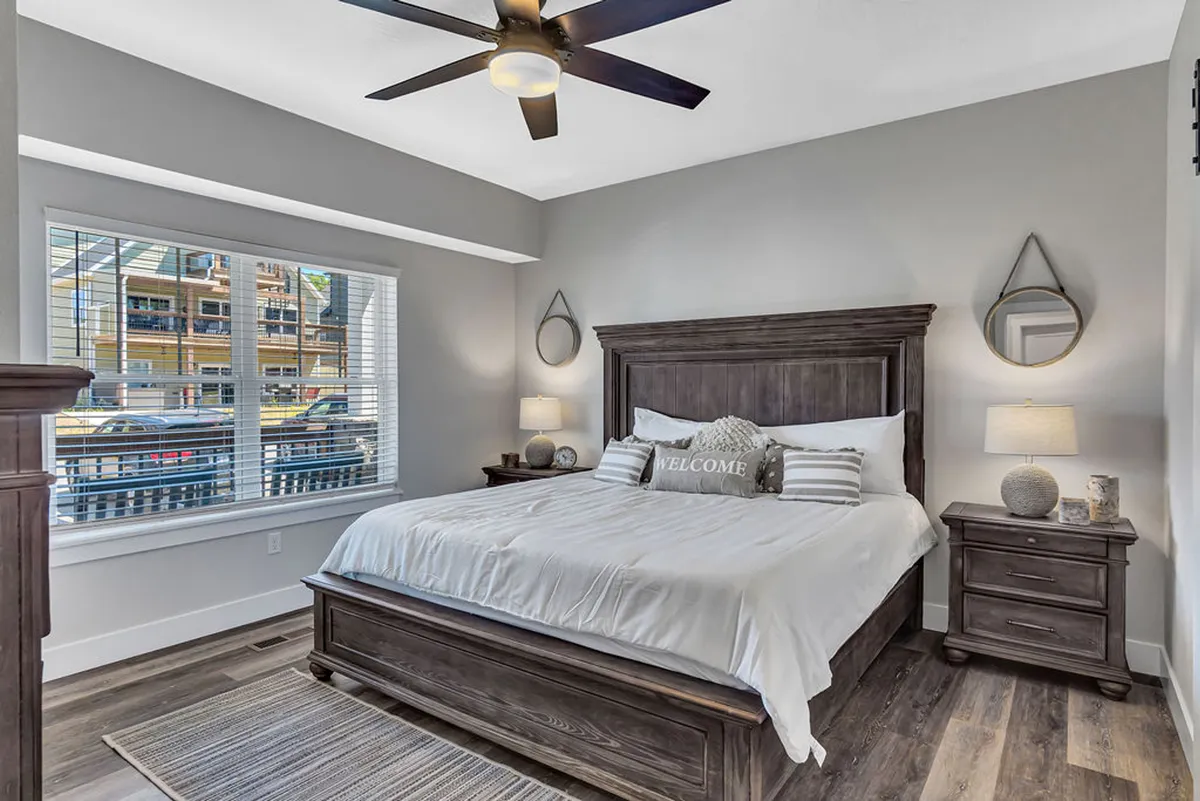 A king bedroom with a plush bed, large windows letting in natural light, matching nightstands, decorative pillows, and subtle wall accents. The overall vibe is cozy and tranquil, perfect for restful retreats.