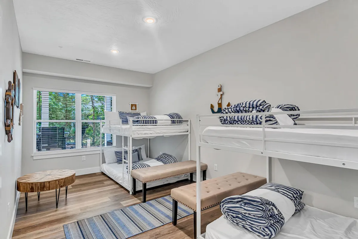 A vibrant and playful bunkroom featuring multiple bunk beds, a cozy seating area, and whimsical wall art. The space feels inviting, designed for kids to enjoy sleepovers and playtime in a safe, fun environment.